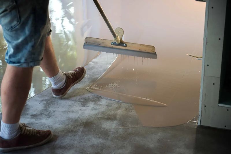 Installer in spiked shoes spreading a floor coating
